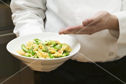 Kellner serviert Farfalle mit Gemüse