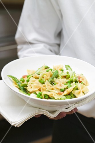 Kellner serviert Farfalle mit Gemüse