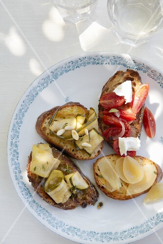 Crostini topped with tomatoes, goat's cheese, onion and courgette