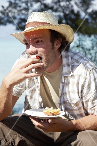 Young man in straw hat eating crostini