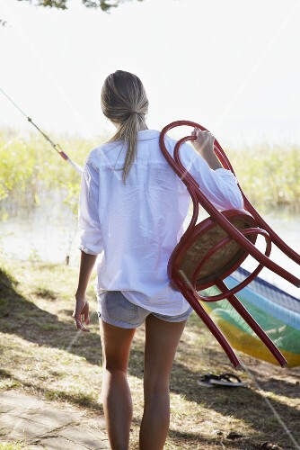 Young woman with a chair by a lake
