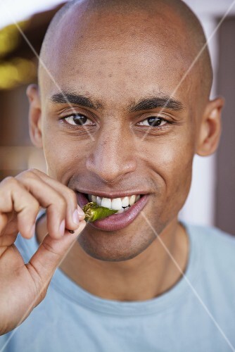 Young man biting into a pepper