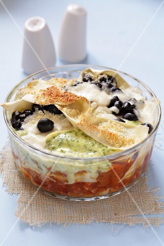 Lasagne with fish and olives in glass dish