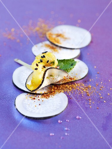 Slices of radish with pineapple and black sesame seeds