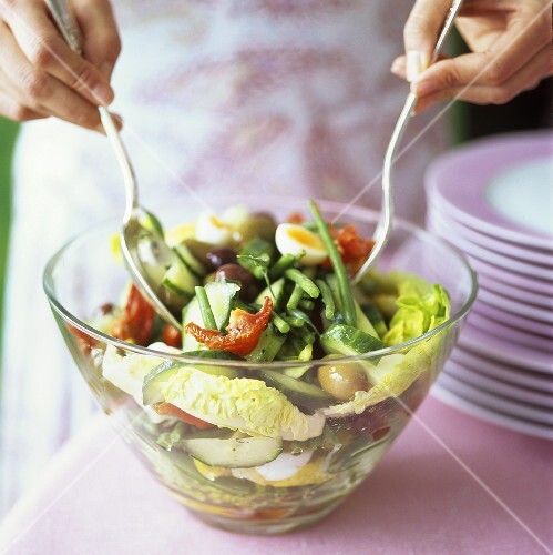 Gemüsesalat mit gekochtem Ei in Salatschüssel vermengen