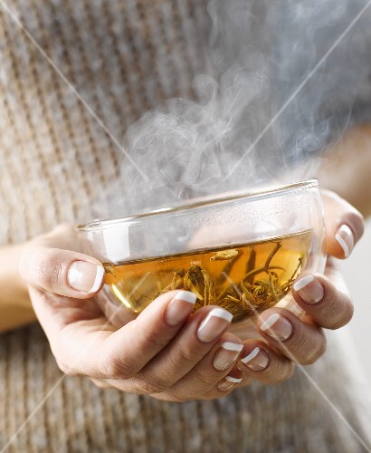Woman holding a steaming cup of jasmine tea in her hands