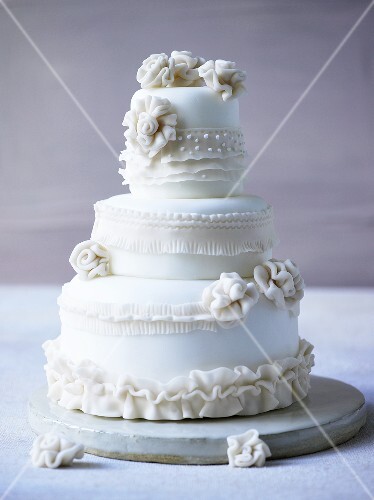 Three-tiered white wedding cake decorated with fondant flowers