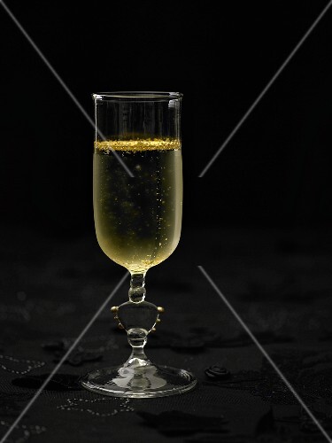 A glass of sparkling wine with gold leaf