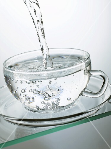Heisses Wasser in eine Glastasse giessen