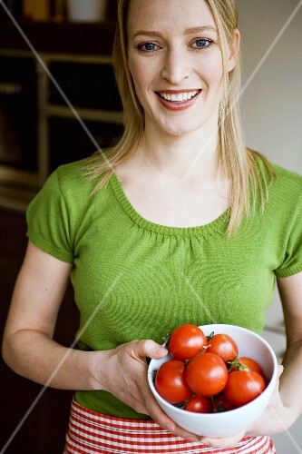 Junge Frau hält eine Schüssel mit Tomaten