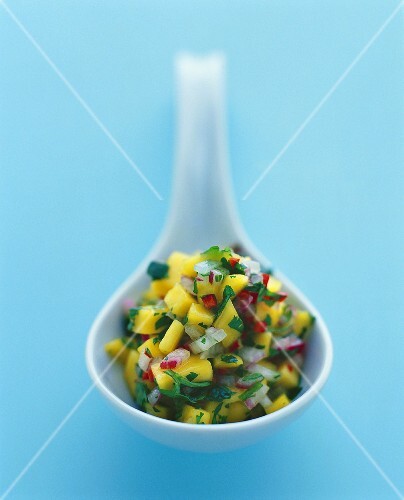 Mango salsa with herbs on spoon