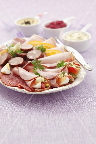 Cold cuts platter with salami, ham rolls, sausage and various sauces