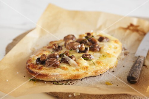 Small mushroom and Pecorino pizza on baking parchment