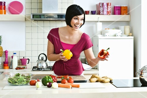 Woman with fresh vegetables in kitchen