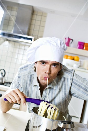 Man in chef's hat eating spaghetti out of pan
