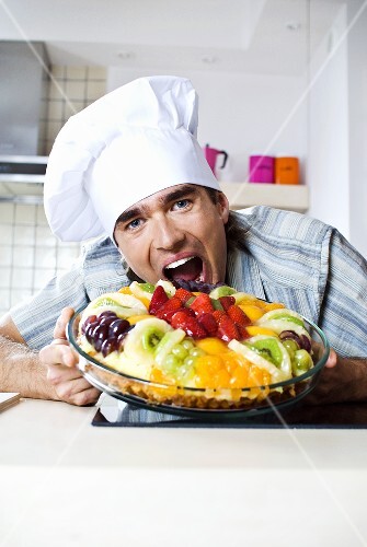 Man pretending to take a bite out of a fruit tart