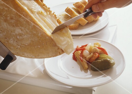 Scraping Melting Cheese from a Loaf of Raclette