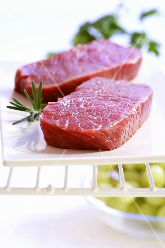 Two beef steaks with rosemary on a platter
