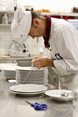 Chef decorating plate with chocolate piping