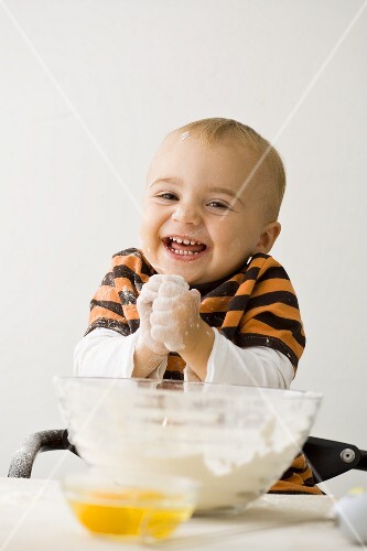 Small boy with floury hands in front of bowl of flour