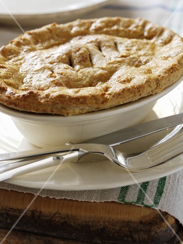Beef pie in a pie dish with knife and fork