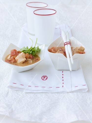 Two bowls of chicken breast in tomato and coconut sauce