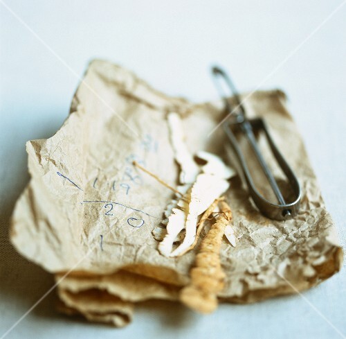 Pastinakenschale mit Schäler auf brauner Papiertüte