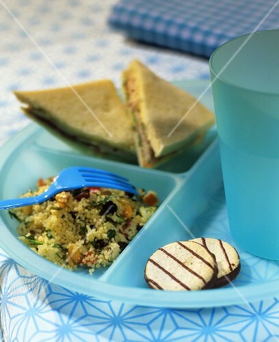 Couscous salad, sandwiches and biscuits on plastic plate