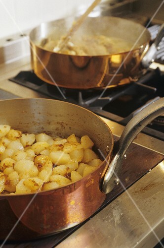 Fried potatoes in a copper frying pan on a cooker