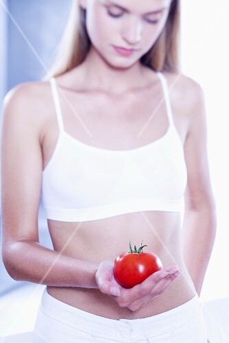 Young woman holding a tomato