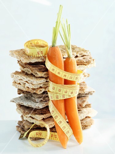 A stack of crispbread and carrots with tape measure