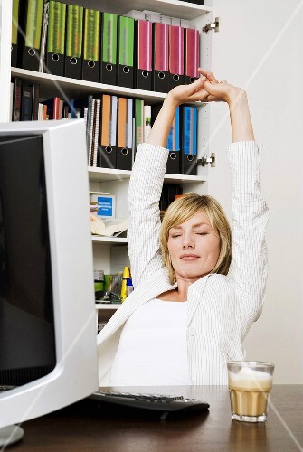 Young businesswoman stretching arms, eyes closed