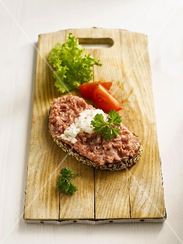 Slice of bread with minced meat on chopping board, close-up