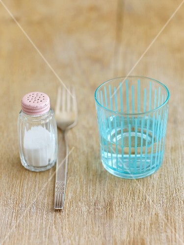 Salzstreuer, Gabel und Wasserglas auf Holzuntergrund