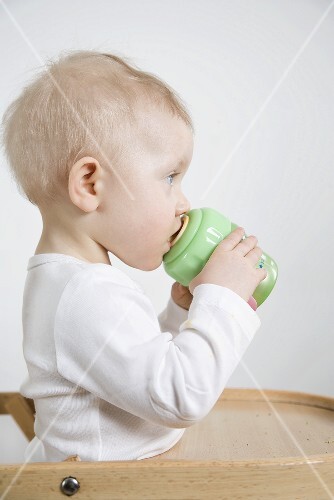 Small child drinking out of a training cup