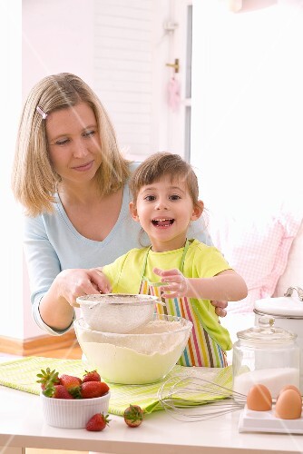 Mother and daughter sieving flour into a bowl