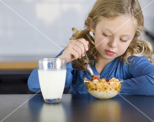 Girl having cornflakes and milk for breakfast