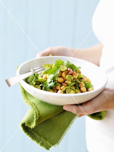 Frau hält Bohnen-Kichererbsen-Salat mit Koriandergrün