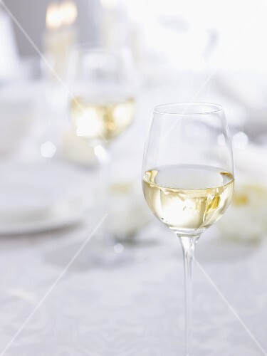 Glass of white wine on table laid for special occasion
