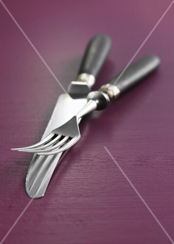 Knife & fork with wooden handles on purple wooden background