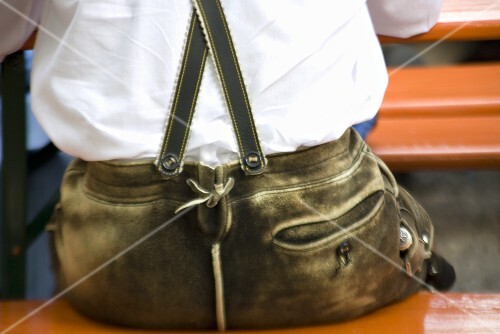 Man in Lederhosen sitting on an ale bench