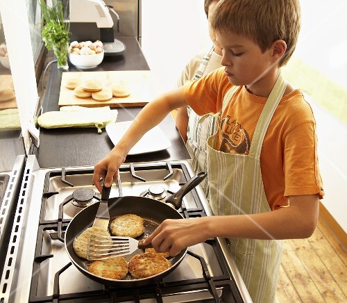 Two boys frying fish cakes