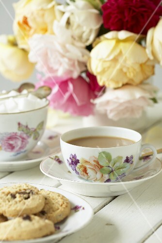 Cup of tea, sugar cubes, cookies and roses