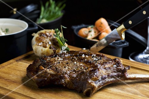 Beefsteak on chopping board, garlic, carrots