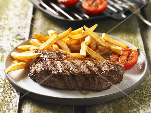 Grilled steak with chips and grilled tomato