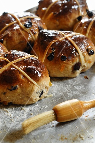 Hot cross buns on a baking tray with pastry brush