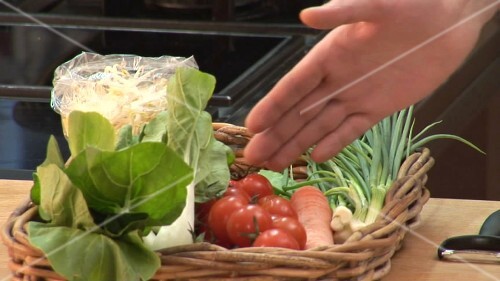 Hand showing basket of vegetables