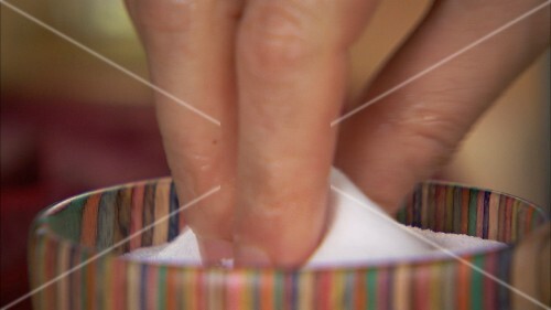 Hand taking salt out of a dish