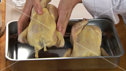 Putting two chickens into a roasting tin