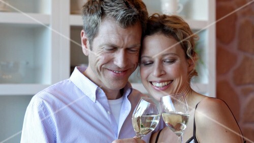 Man and woman clinking glasses of white wine